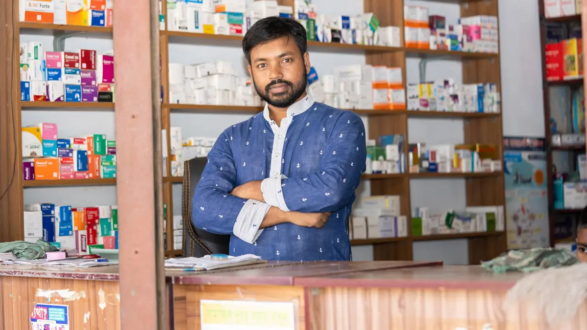 Photo: A confident pharmacist stands behind the counter of a pharmacy in Natore, Bangladesh.