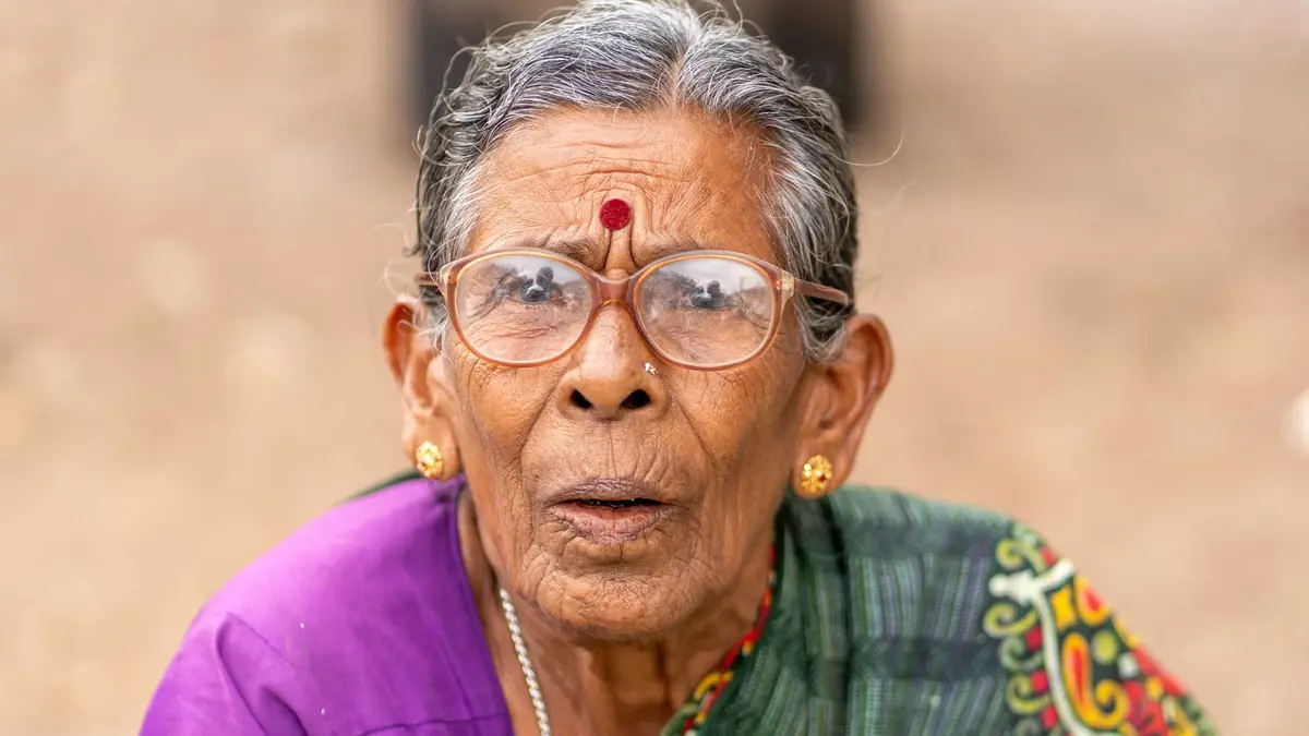 Photo: Close-up portrait of an elderly woman wearing a bindi and traditional clothing.