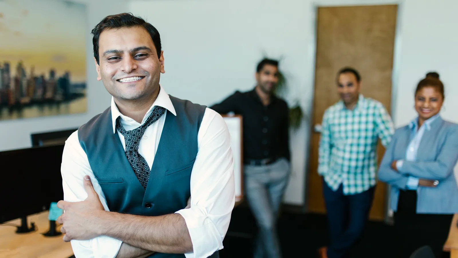 Illustrative scene: a smiling businessman with colleagues in an office