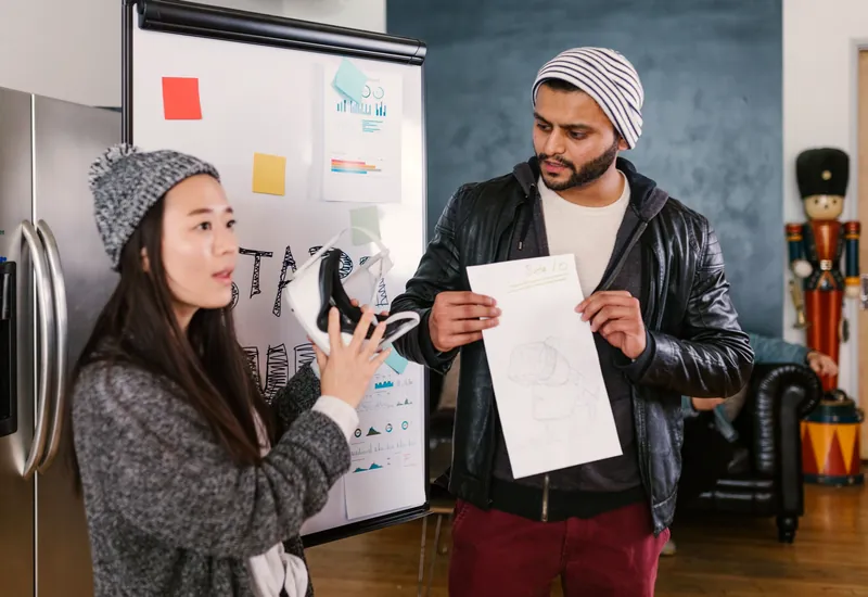 Illustrative scene: two colleagues planning a product with a sketch beside a whiteboard