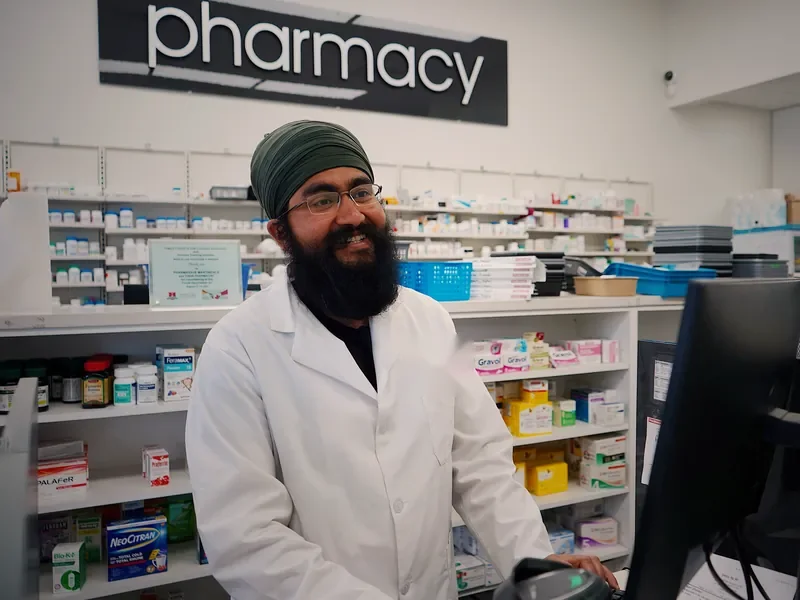 Illustrative scene: a pharmacist smiling at a modern pharmacy counter