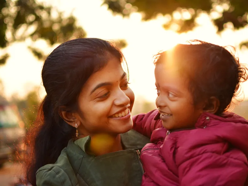 Illustrative scene: a mother smiling at her young child outdoors