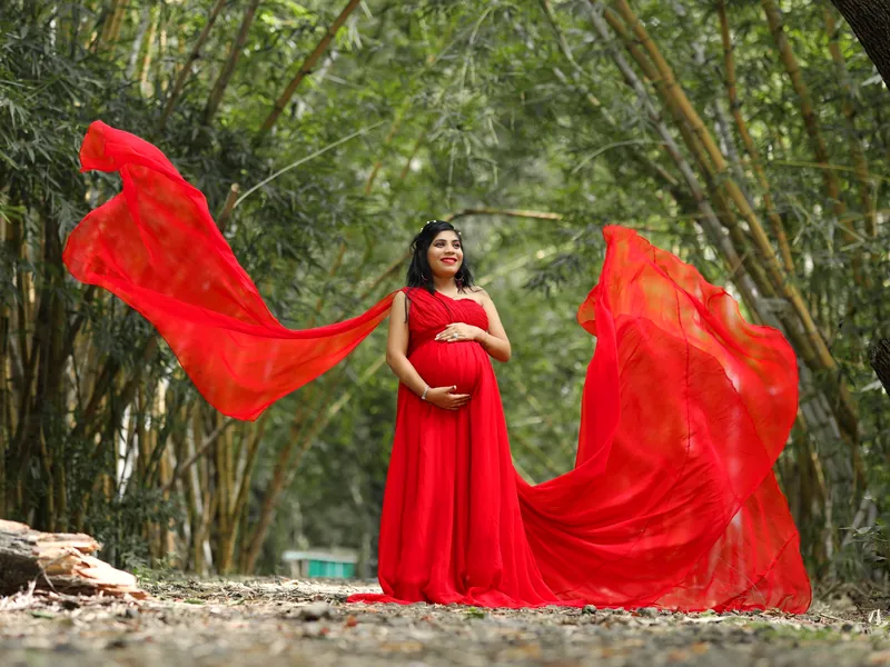 Illustrative scene: an expectant mother in a red gown standing in a bamboo grove